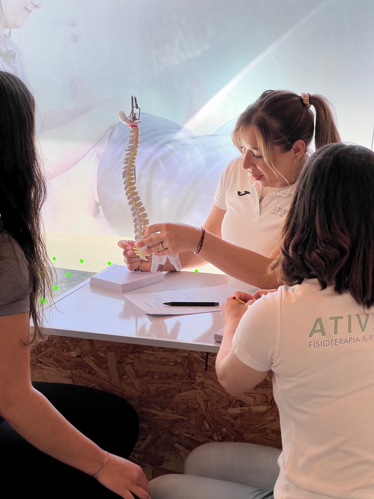 Fisioterapeuta da AtiveFit a explicar a coluna vertebral num modelo anatómico a uma cliente, durante a avaliação